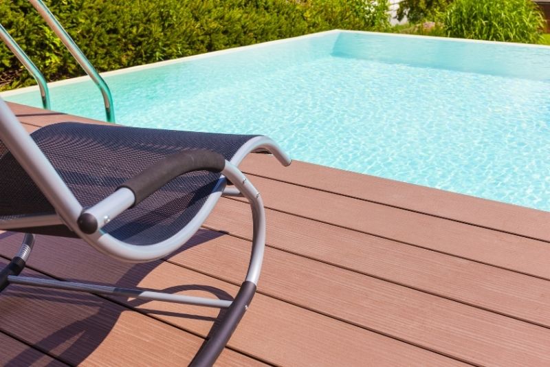clear pool water and a pool deck beside with a chair